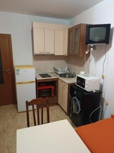 Una pequeña cocina con estufa y microondas. en Stamopolu apartament 1, en Primorsko