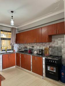 a kitchen with wooden cabinets and a stove at CasaComfy Bukoto in Kampala