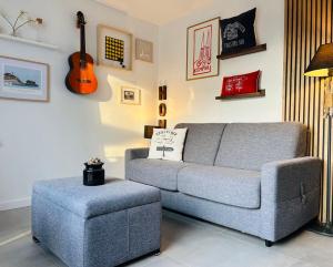 sala de estar con sofá gris y guitarra en Studio & Spa La Discrète, en Saint-Évarzec