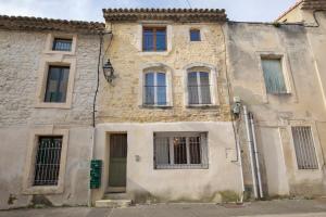 un antiguo edificio de piedra con ventanas en una calle en Le Ginger Tricastin, en Lapalud