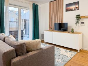 ein Wohnzimmer mit einer Couch und einem Fernseher auf einem Schrank in der Unterkunft Suite Rosa Disneyland Paris - Rentaway BnB in Coupvray