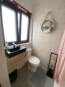 a bathroom with a toilet and a sink and a window at Cici Guesthouse in Caminha