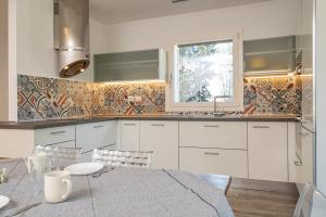 eine Küche mit weißen Schränken und einem Tisch und einem Fenster in der Unterkunft La Casina Bianca in Santa Maria degli Angeli + 58 Fotos