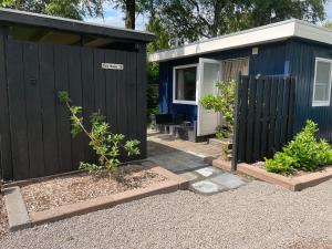 a blue and black shed with a black fence at Tiny House 76 Leekstermeer in Matsloot
