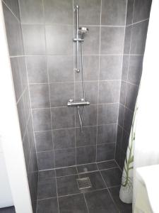 y baño con ducha y azulejos grises. en Skovgårdens Apartment, en Grindsted