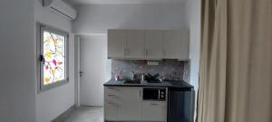 a kitchen with white cabinets and a sink and a window at Aenaon Corfu Luxury Apartments #05 - Athena Apartment in Ipsos