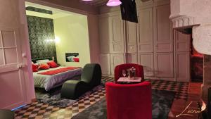 a bedroom with a bed and a chair and a table at L'Écrin Love Room Spa privatif Orbec in Orbec-en-Auge