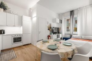 ein weißes Apartment mit einem Tisch und einem Bett in der Unterkunft Casa San Siro-Stadio - Stadio e Metropolitana in Mailand