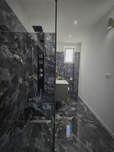 a bathroom with a black marble shower stall at Nevis Apartment in Hunedoara +6 photos