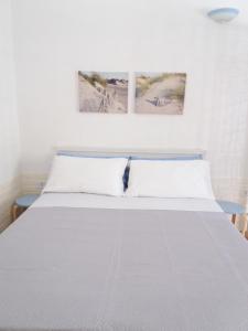 a white bed with two pictures on the wall at M & G - Casa Vacanze in Santa Maria al Bagno