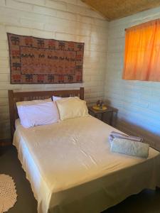 ein Schlafzimmer mit einem Bett mit weißer Bettwäsche und einem Fenster in der Unterkunft Vila Mangueira in Cavalcante