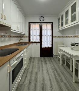 a kitchen with white cabinets and a table and a clock at Hostería Miguel Angel in Santillana del Mar