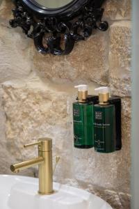 a bathroom sink with two green bottles on the wall at Design rooms ANIMA MUNDI CityCentre right next to Diocletian's Palace in Split