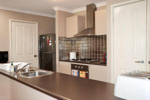 a kitchen with a sink and a black refrigerator at Come dine with me at Jo in Baldivis