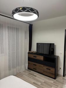 ein Schlafzimmer mit einem TV auf einer Kommode und einem Bett in der Unterkunft DOL House - Apartment in Râșnov