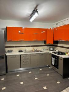 Eine Küche mit orangefarbenen Schränken und Edelstahlgeräten in der Unterkunft DOL House - Apartment in Râșnov