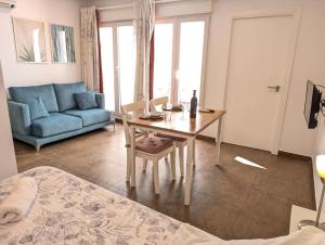 uma sala de estar com uma mesa e um sofá azul em Estudios en la playa em Valência