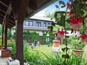 a house with a garden with red and white flowers at Apartment near Altdöbern Castle & Spreewald in Altdöbern +2 photos