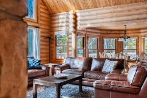 a living room with leather furniture in a log cabin at Fiddler Lake Resort - Deer 76 in Mille-Isles
