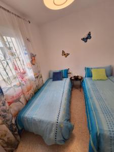 two beds in a room with butterflies on the wall at El Rinconcito Mágico in El Bosque