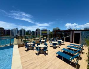 a rooftop deck with tables and chairs and a pool at Studio TEC Centro de convenções Smart Home in Salvador