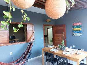 a dining room with a wooden table and two lights at Casa Mar in Passo de Camarajibe