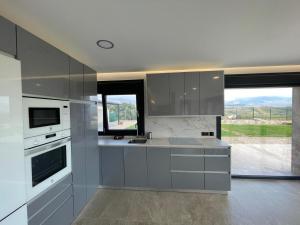 a kitchen with gray cabinets and a large window at La Portilla de la Vera in Collado