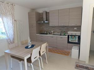 a kitchen with a wooden table and chairs at Alloggio La Goccia, appartamento Mare in Rosolina