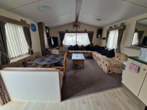 a living room with a couch and a table at Ocean Breeze Hideaway 2 Bed Pet Friendly Static Caravan In Clarach Bay in Aberystwyth