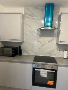 a kitchen with white cabinets and a stove top oven at Jay3 Suites - Spacious Entire Apartment in London in Dagenham +8 photos