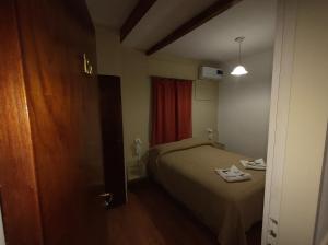 a small bedroom with a bed and a red curtain at Hotel Viñas San Rafael in San Rafael