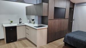 cocina con armarios de madera y TV de pantalla plana. en Casa 1982, en Manizales