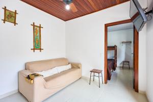 sala de estar con sofá y cruz en la pared en Casinha da Enseada, en Ubatuba