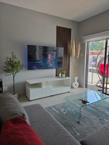 a living room with a couch and a tv on the wall at WeThusi-CBD in Mbabane
