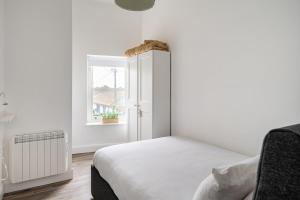 een witte slaapkamer met een bed en een raam bij 1 Cathedral Place - Cathedral Townhouses Cobh in Cobh +18 foto's