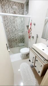 a bathroom with a toilet and a sink and a shower at Sobrado em Condomínio Praia das Astúrias in Guarujá