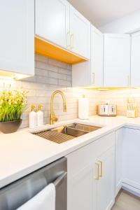 Una cocina blanca con gabinetes blancos y un fregadero. en Luxury 2 Bed 2 Bath East Boston, en Boston