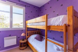 a bedroom with two bunk beds and a purple wall at La Terrasse d'Azur - Vue sur la mer in Lapalme