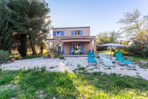 a house with chairs and an umbrella in the yard at La Terrasse d'Azur - Vue sur la mer in Lapalme