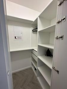 a walk in closet with white shelves and a door at Apartament Pod Żaglami 4 in Sława