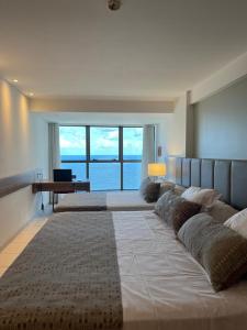 una grande camera da letto con tre letti e una grande finestra di Frente Mar - Beach Class Executive - Boa Viagem - Pina - 21º andar a Recife