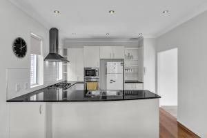 a kitchen with white cabinets and a black counter top at Cozy Home in Epsom in Auckland