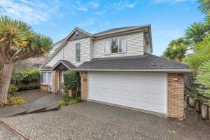 a house with a white garage and a tree at Cozy Home in Epsom in Auckland
