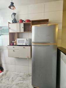 a stainless steel refrigerator in a kitchen with a microwave at Apartamento para aproveitar a praia in Praia Grande