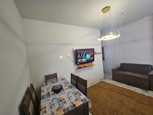 a living room with a table and a couch and a television at Apartamento para aproveitar a praia in Praia Grande