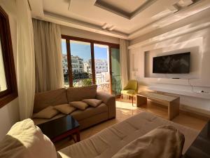 a living room with a couch and a tv at Sharm Hills Resort - 2Bedroom with Pool View and Beach Access in Sharm El Sheikh