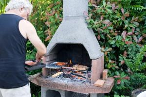 a woman cooking food in an outdoor oven at Chambre d'Hôtes Oeuil de Bouc in Madiran