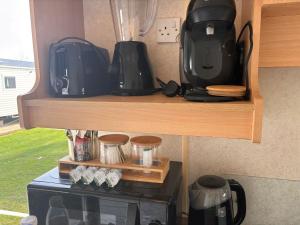 a shelf with two coffeemakers on top of a microwave at Adventure Van 6 berth St Osyth Beach Park in Saint Osyth