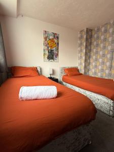 a bedroom with two beds with orange sheets at Families and Contractors Dudley DY1 in Lower Gornal