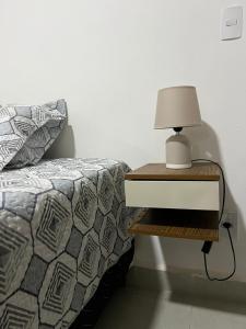 a bed with a nightstand with a lamp on it at Souza Lofts Centro Praça Tiradentes in Teófilo Otoni +11 photos